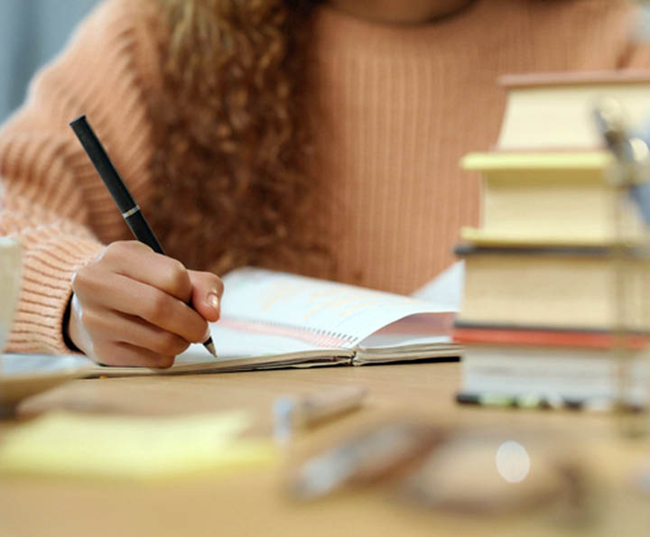 Woman student study, writing and reading education book for an exam or test at school, college or university. Academic girl studying and learning for knowledge while at a table with notes on paper